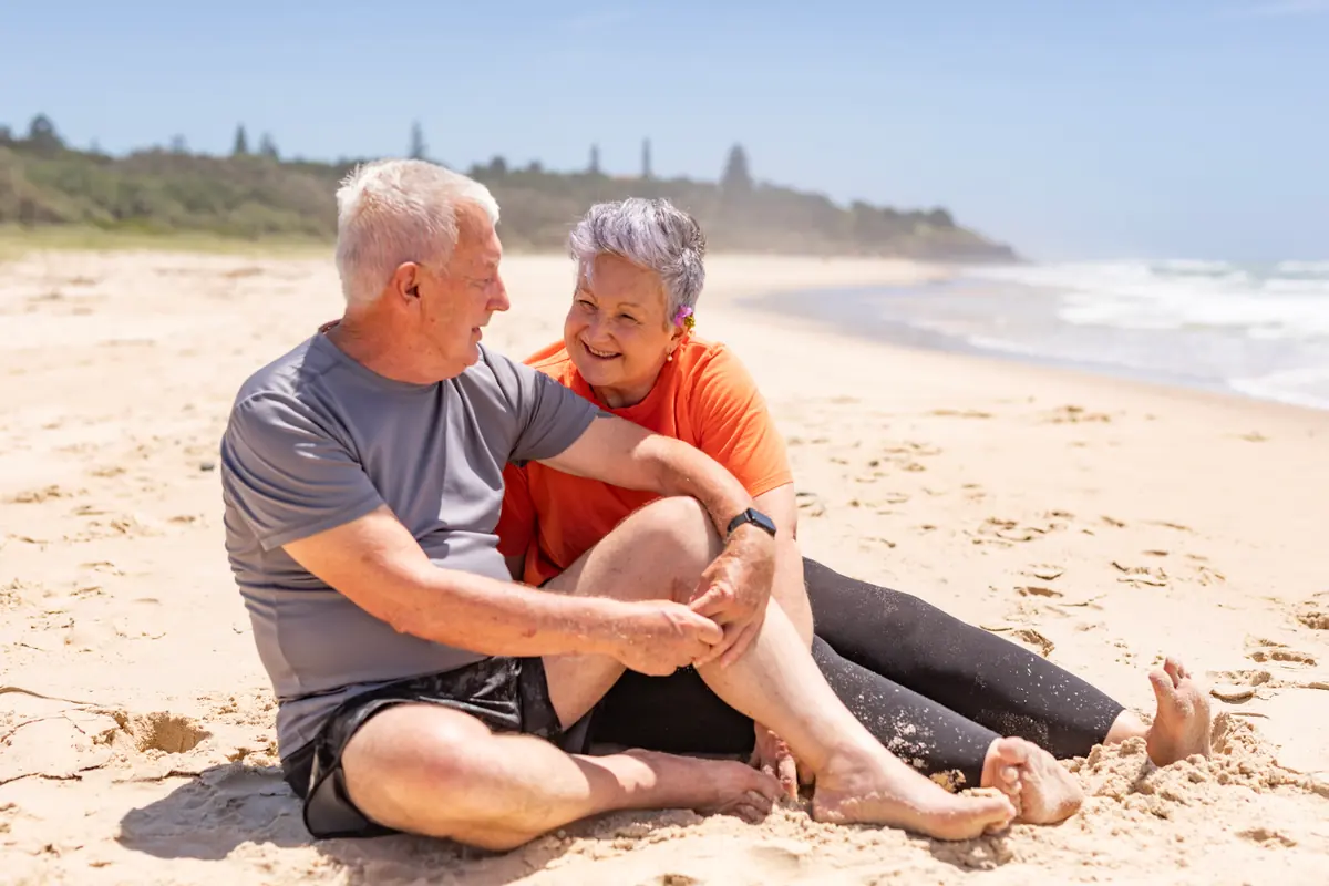 An older couple sitting together on a beach