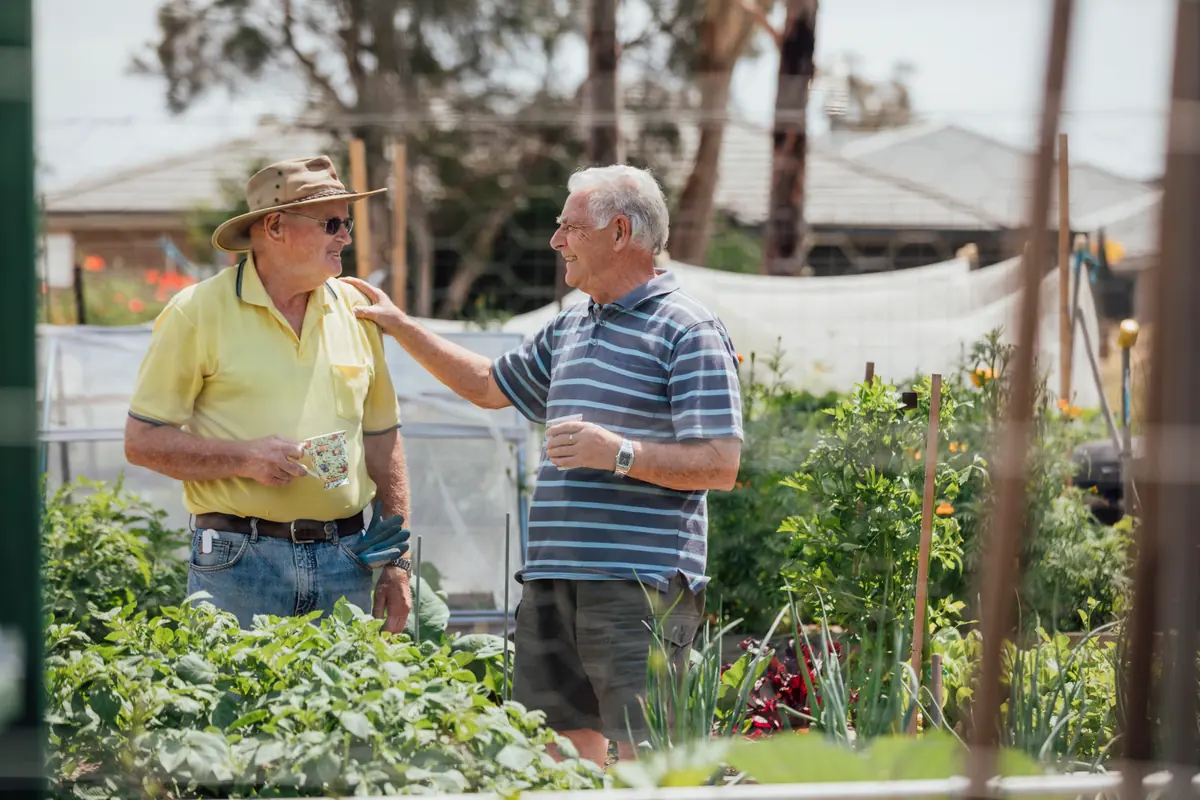 Two older men talking together in a community garden